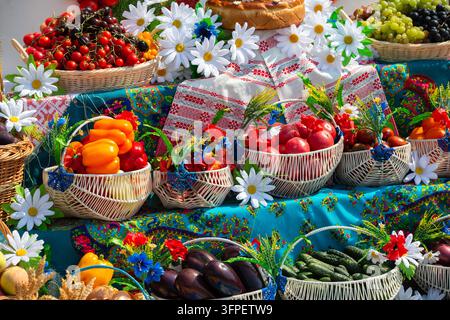 A colorful assortment of fresh fruits and vegetables arranged in woven baskets showcases summer's bounty at a local market. Bright flowers add to the Stock Photo