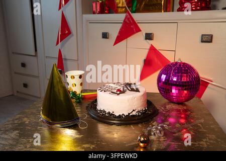 A birthday or celebration scene shows a cake with decorations, party hats, and colorful banners set on a table at home. Stock Photo