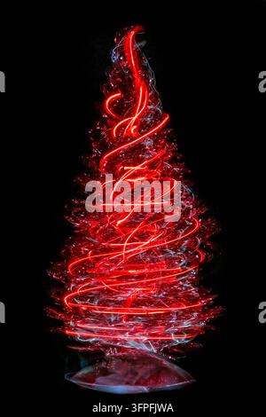 Small Christmas tree background formed from swirling red lights on a black background with festive seasonal atmosphere and copy space Stock Photo