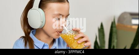 A gen Alpha girl studies with her headphones, sipping juice in a cozy workspace, banner Stock Photo