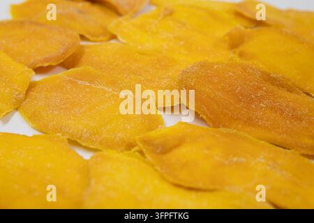 Golden Yellow Dried Mango Slices Arranged on a White Surface Stock Photo