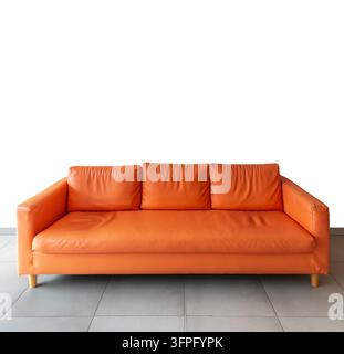 three-seater orange leather sofa with wooden legs, positioned on  gray tiled floor isolated on white backdrop with clipping path, ideal for interior d Stock Photo
