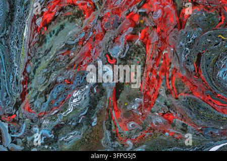 Complex textured liquid composition featuring bold red, grey, and blue paint cells mixing together Stock Photo