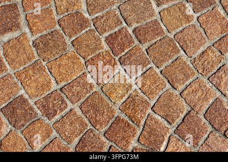 Warm reddish brown porphyry cobblestone pavement texture arranged in arched fan pattern for classic European street design with copy space Stock Photo