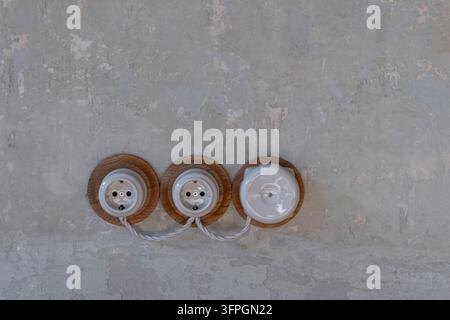 Vintage ceramic electrical sockets and light switch with braided cable on concrete wall background Stock Photo