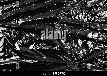Abstract crumpled black plastic film texture close up. Stock Photo