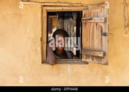 Woman smiling while leaning out of a window, Bono East Region, Kintampo, Ghana Stock Photo