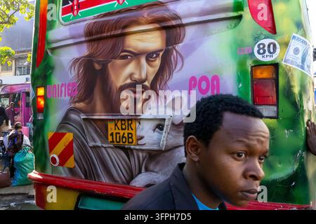 Back of a green matatu with an airbrushed painting of Jesus holding a lamb and a young man in a black jacket passing in front, Nairobi County, Nairobi Stock Photo
