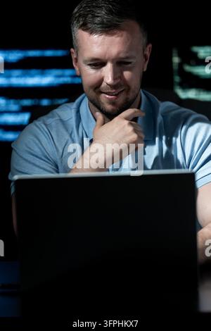 Programmer works in technology workplace. Programmer writes coding for software system. Programmer monitors network and cybersecurity threats Stock Photo