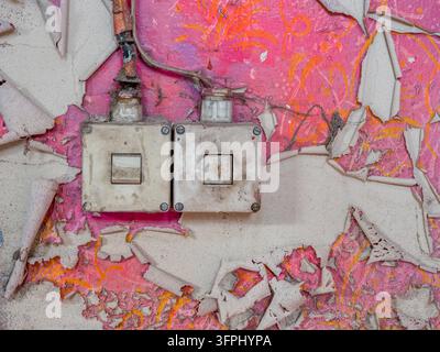 A charming retro light switch mounted on a soft pink wall, capturing the simple beauty of vintage interior design. The aged switch, classic form, and pastel surface create a nostalgic atmosphere with a warm, timeless appeal. Ideal for lovers of retro decor Stock Photo