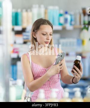 Girl in summer clothes scans code on cough syrup to check expiration date Stock Photo