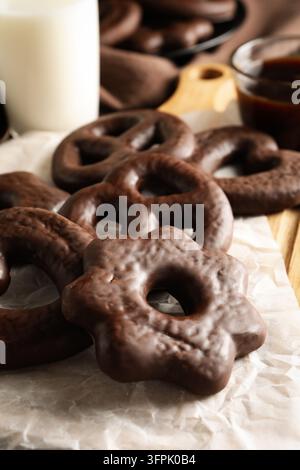Chocolate gingerbread cookies. Close up of gingerbread cookies in chocolate glaze on baking paper. Homemade chocolate gingerbread in flower shape Stock Photo