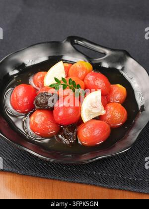 Preserved Plum Marinated Cherry Tomatoes on Black Ceramic Plate, Restaurant Appetizer Stock Photo