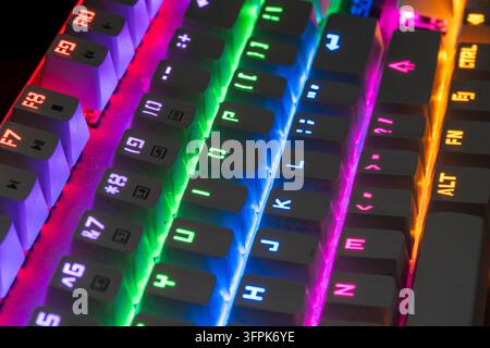 View along gaming keyboard with vibrant rainbow LED back lighting, combining technology and entertainment. Keys and key rows illuminated. Stock Photo