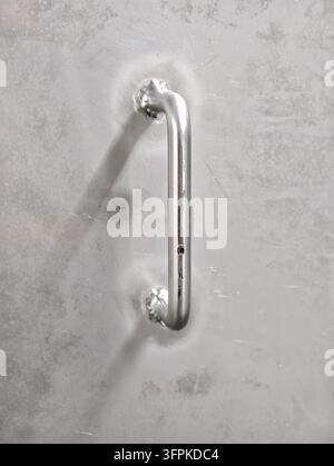 Close-up view shows sleek metallic door handle fixed on brushed steel. Vertical pull bar with rounded ends and smooth reflective finish, with soft sha Stock Photo