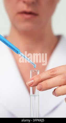 Scientist adding liquid with pipette into a test tube during a chemistry experiment in a laboratory Stock Photo