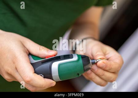 Close up of hands holding an electric screwdriver ready to fasten screws during a diy project. The man works carefully with power tools while building Stock Photo