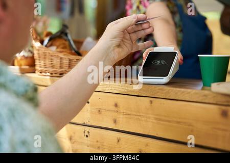 Close Up Of Person Making Contactless Payment For Takeaway Coffee Stock Photo