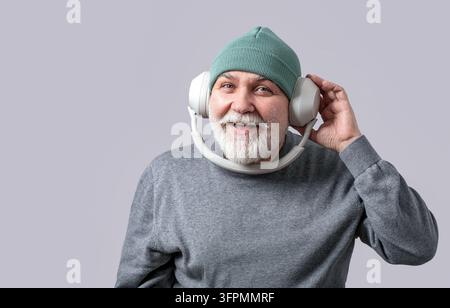 Portrait of smiling mature bearded man listening to music in headphones. Technology concept, fun. Senior retired elderly man listens to music, dances Stock Photo