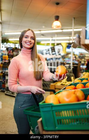 Young woman grocery shopping for fresh oranges in supermarket Stock Photo