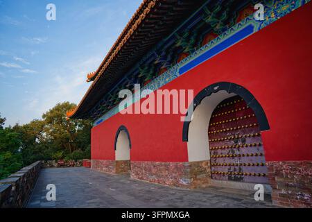 NANJING, China - 2026/10/08: Detailed view of painted wooden brackets and glazed tiled eaves above a red wall with an arched doorway at the Ming. Stock Photo