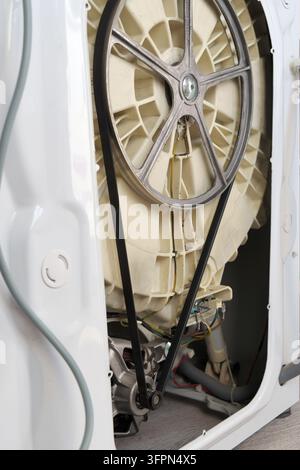 Photo of the back of a broken washing machine with motor and drive belt . Repair of the washing machine. Stock Photo