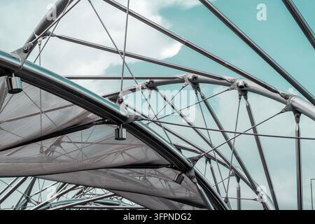 Metal structures with mesh and cables under a blue sky, forming an abstract modern architectural design Stock Photo