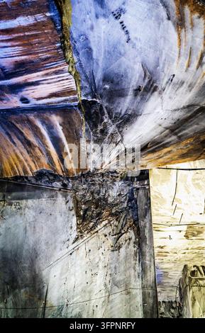 Abstract close-up of weathered painted wood and cracked surfaces, showing layered blue, brown, gray, and white textures with rough aged details. Stock Photo
