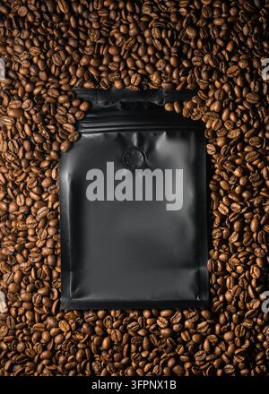 Black coffee bag lightly covered with roasted beans in vertical top view for branding, packaging and product presentation Stock Photo