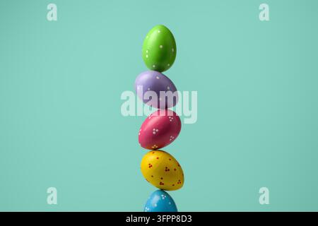Colorful polka dot Easter eggs rise in tall stack on mint turquoise background, clean seasonal still life with wide copy space. Stock Photo