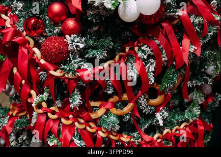 Christmas tree decorated with red ribbons, ornaments and gingerbread chain Stock Photo