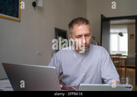 Adult student using laptop and tablet for online learning, education, training, upskilling, reskilling course and professional skill development at home. Stock Photo