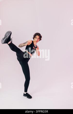 Slim woman in black sportswear practicing a leg kick Stock Photo