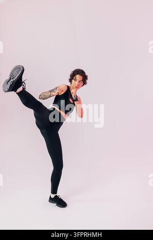 Slim woman in black sportswear practicing a leg kick Slim woman in black sportswear practicing a leg kick Copyright: xxArtemxVarnitsinx Stock Photo