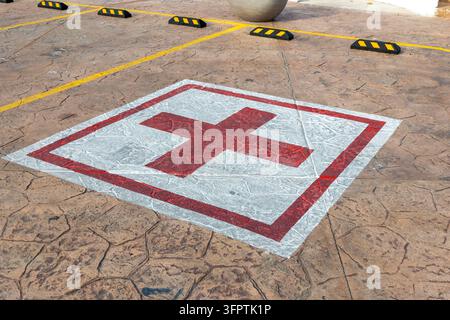 Painted Red Cross Symbol in Square on Stamped Concrete Parking Lot, Emergency Medical Parking Space Floor Marking High Angle View Stock Photo