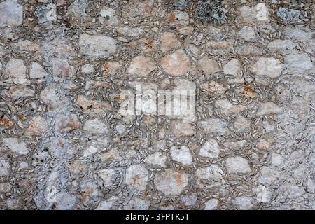 Ancient Rubble Stone Wall with Limestone Blocks and Small Stone Chinking Chips Set in Gray Lime Mortar, Rough Masonry Detail Stock Photo