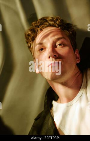 Portrait of Thoughtful Man Looking into Camera with Dramatic Shadows Stock Photo