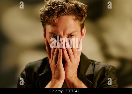 Portrait of Stressed Man Holding Face Expressing Anxiety Stock Photo