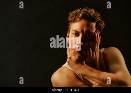 Portrait of Thoughtful Man Holding Face in Dramatic Studio Lighting Stock Photo