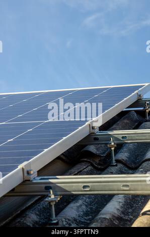 Close up view of photovoltaic modules mounted on a weathered tile roof ...