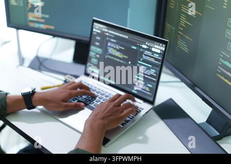 Close up of developer hands coding on laptop computer with screens Stock Photo