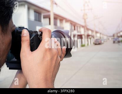 Close up hands of Young Asian photographer taking pictures of housing estates. Property and real estate concept. Stock Photo