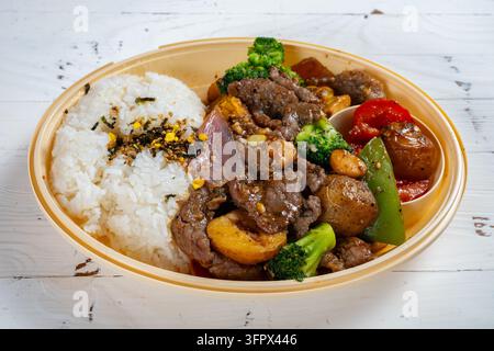 Beef with broccoli and assorted vegetables served with fluffy white rice in disposable lunch bowl Stock Photo
