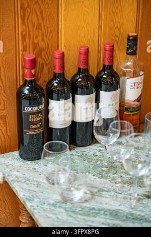 Bottles of port, red Bordeaux wine and Scotch whisky with glasses on a marble sideboard at a shooting lodge in Glen Clova, Scotland Stock Photo