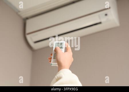 Energy efficiency and climate control, person using remote to adjust air conditioning temperature for home comfort and cooling during summer heat Stock Photo