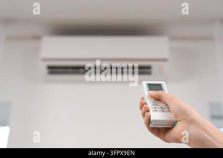 Climate control and energy efficiency, person using remote to adjust air conditioning temperature in home or office for comfort and cooling Stock Photo
