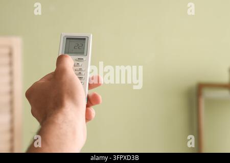 Energy efficiency and climate control, person using air conditioner remote to adjust temperature in home interior for comfort and power saving Stock Photo