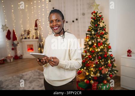 Woman holding tablet celebrating Christmas at home Stock Photo
