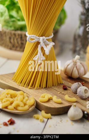 Italian Pasta Cooking Ingredients Spaghetti Macaroni Garlic on Wooden Cutting Board Stock Photo