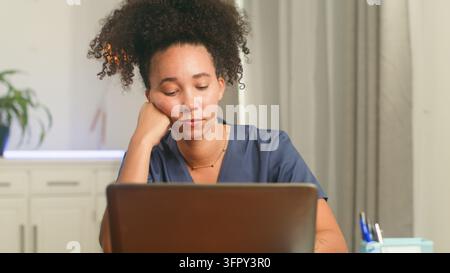 Woman works on laptop with stress and burnout at her desk Stock Photo